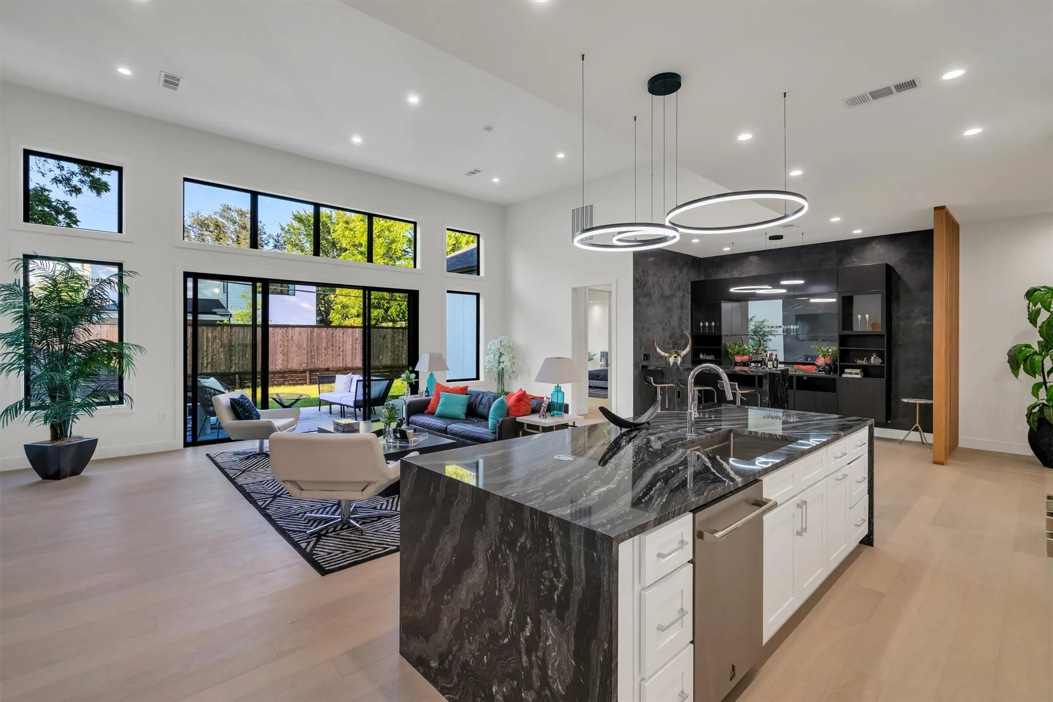 Kitchen with a sink, a towering ceiling, stainless steel dishwasher, recessed lighting, and light wood-style flooring