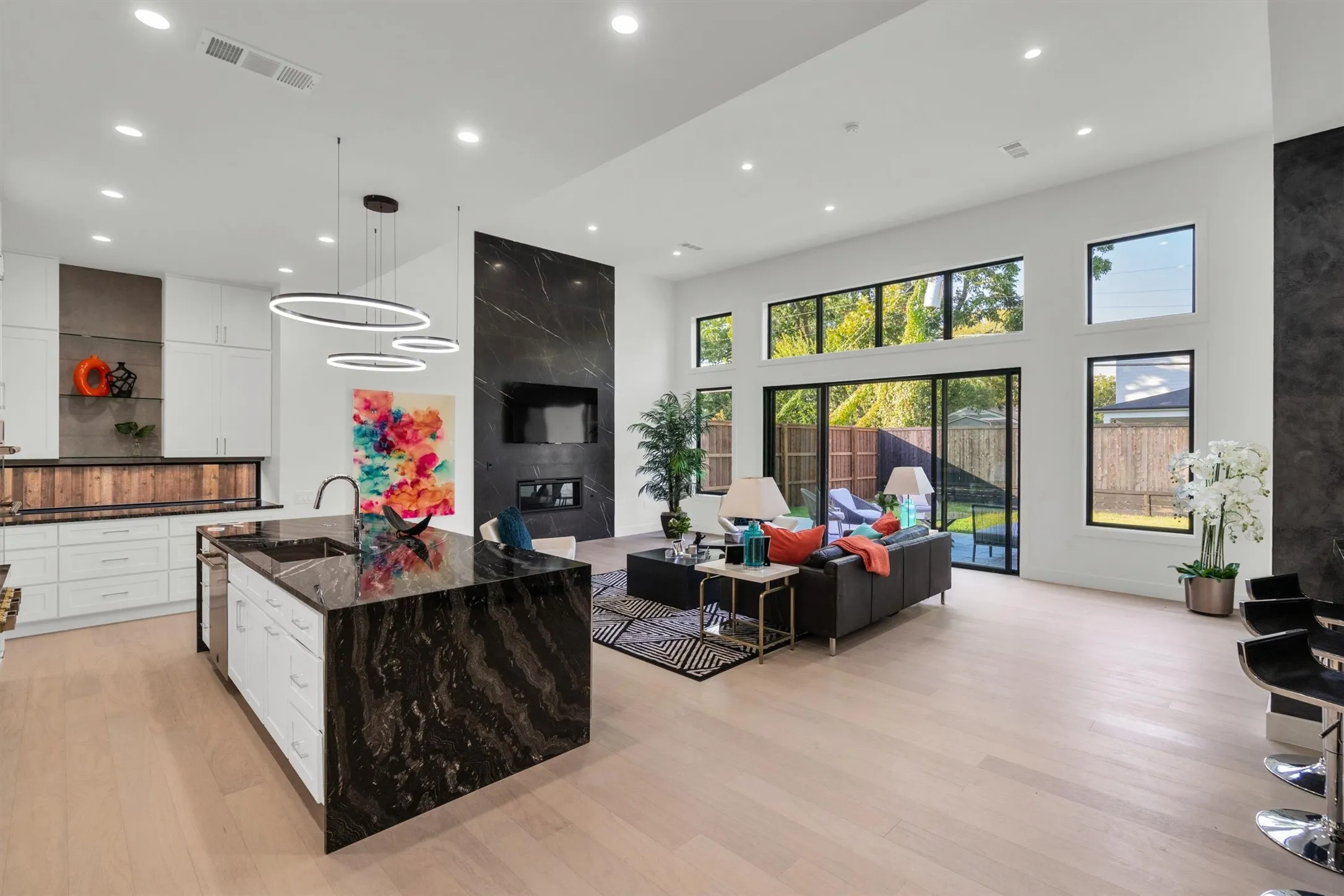 Living area featuring light wood-style floors, recessed lighting, and a high ceiling