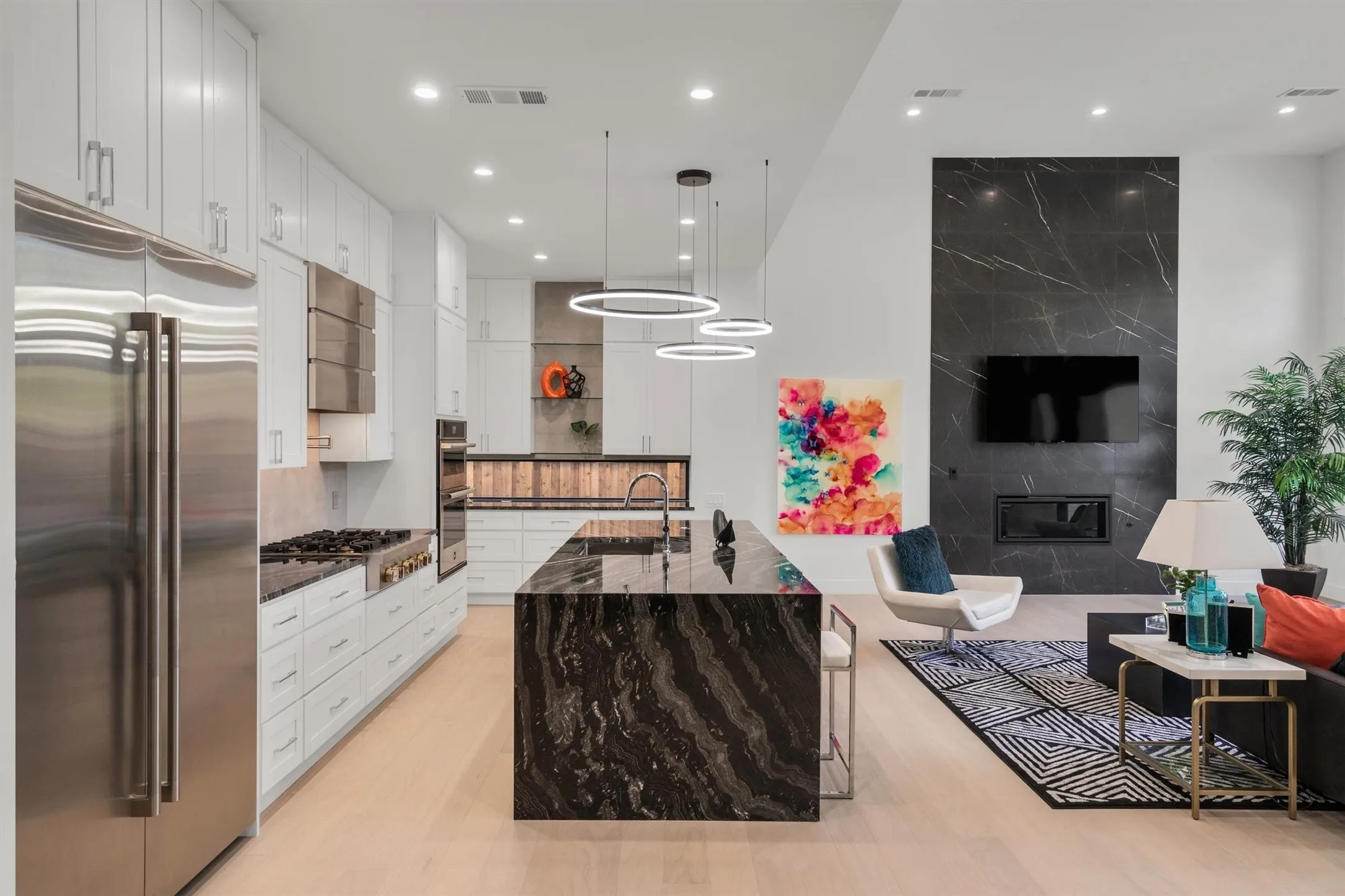 Kitchen featuring stainless steel appliances, a sink, white cabinets, dark stone countertops, and light wood-style floors
