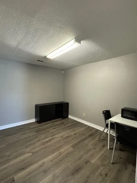 Home office featuring dark wood-style flooring, baseboards, and a textured ceiling