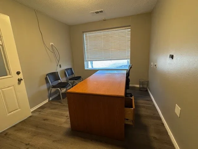 Home office with dark wood finished floors, baseboards, and a textured ceiling