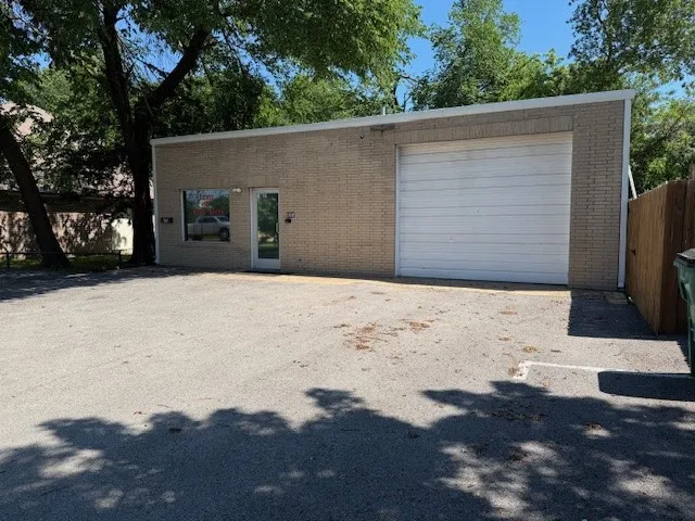 View of front of house featuring brick siding, a garage, and fence