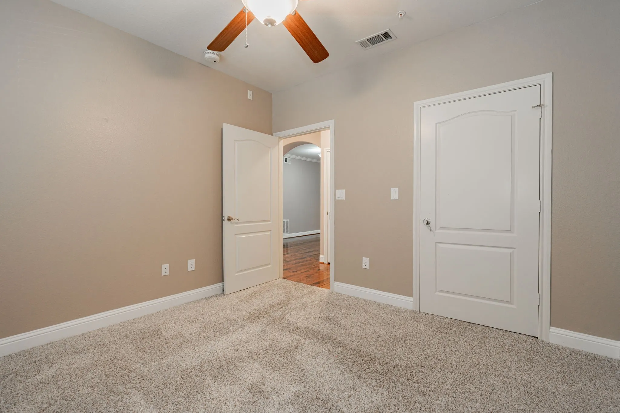 Unfurnished bedroom featuring carpet floors, baseboards, ceiling fan, and arched walkways