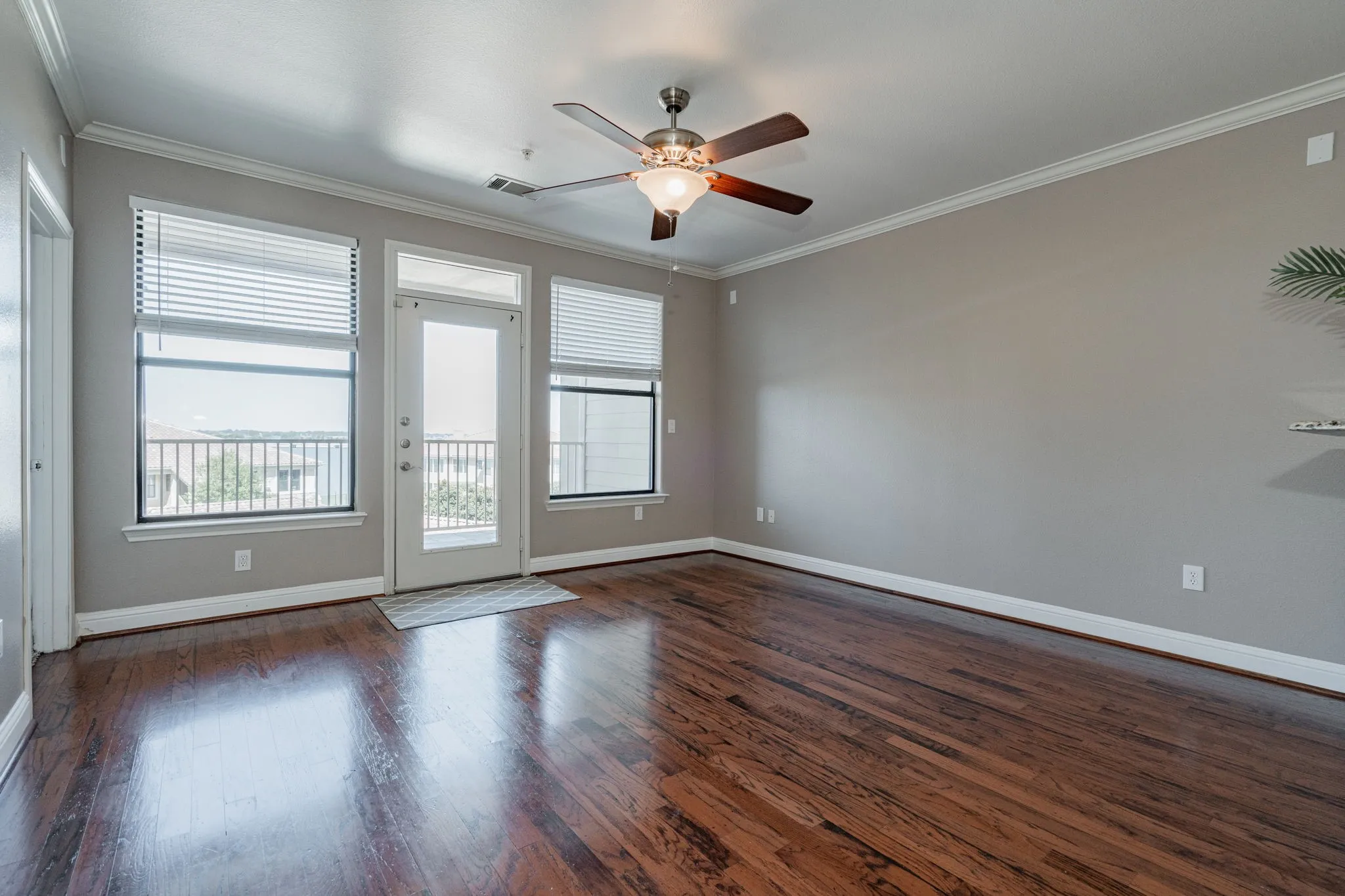 Spare room with healthy amount of natural light, dark wood-type flooring, crown molding, ceiling fan, and baseboards