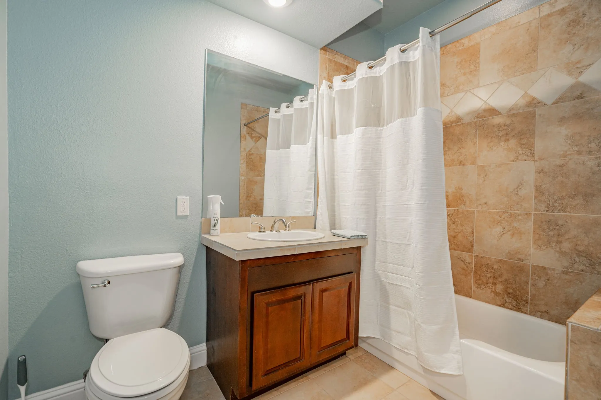 Bathroom with toilet, vanity, shower / bathtub combination with curtain, and tile patterned floors