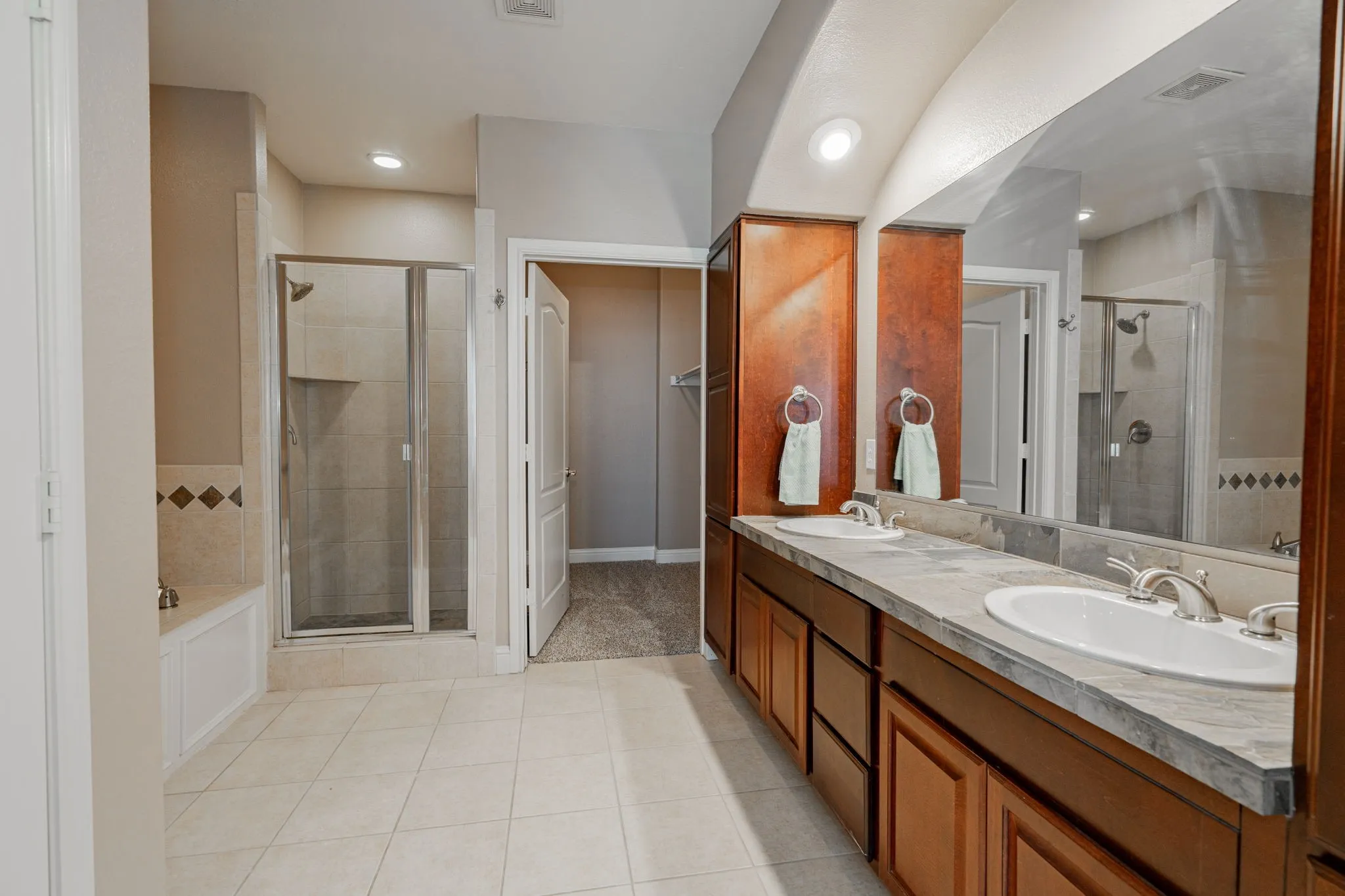Full bathroom featuring tile patterned floors, a stall shower, double vanity, recessed lighting, and a bath