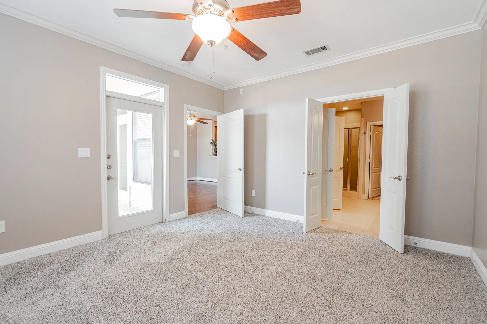 Unfurnished bedroom featuring crown molding, light carpet, baseboards, and a ceiling fan