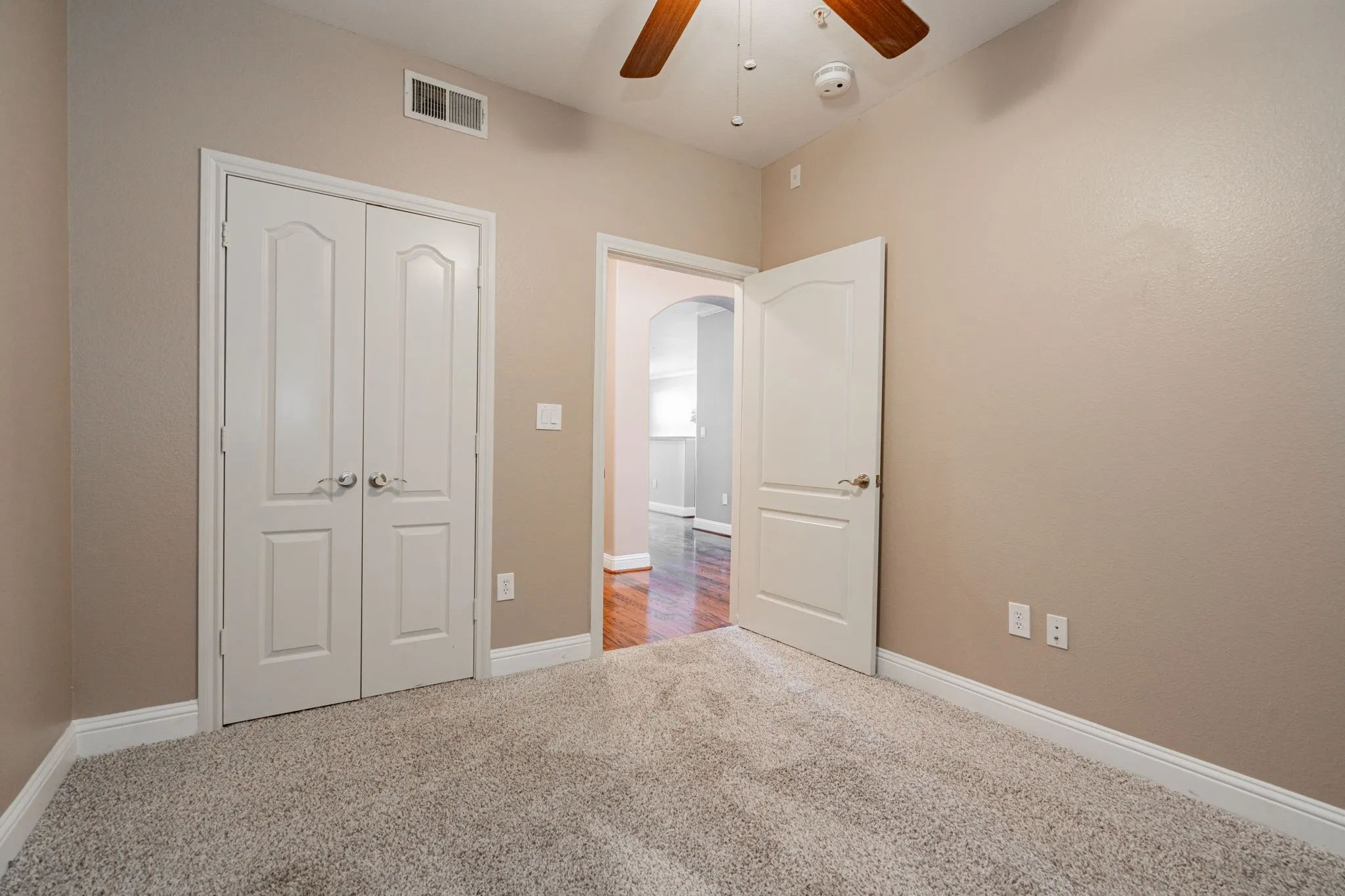 Unfurnished bedroom with carpet flooring, a closet, arched walkways, ceiling fan, and baseboards