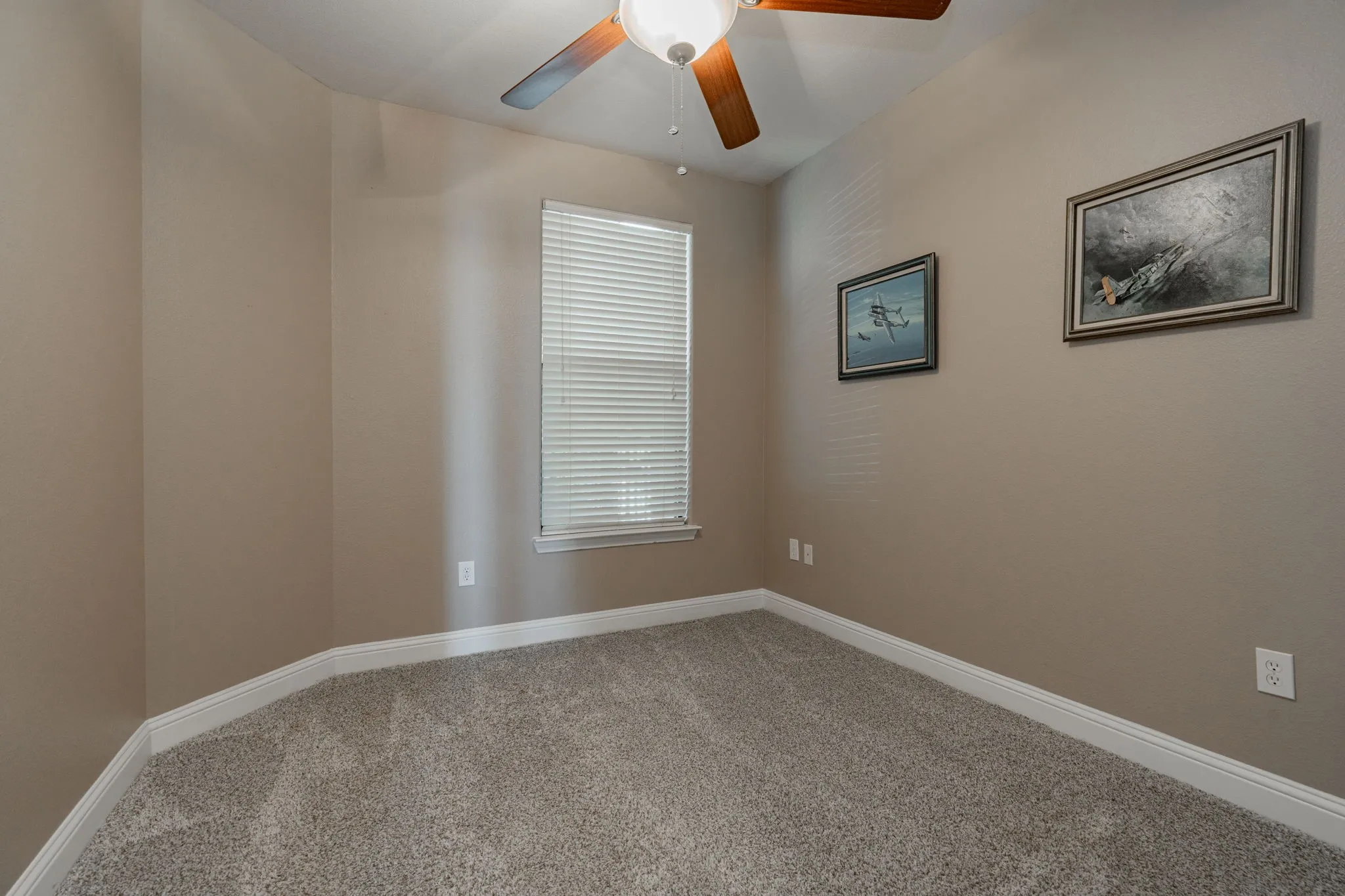 Carpeted empty room featuring ceiling fan and baseboards