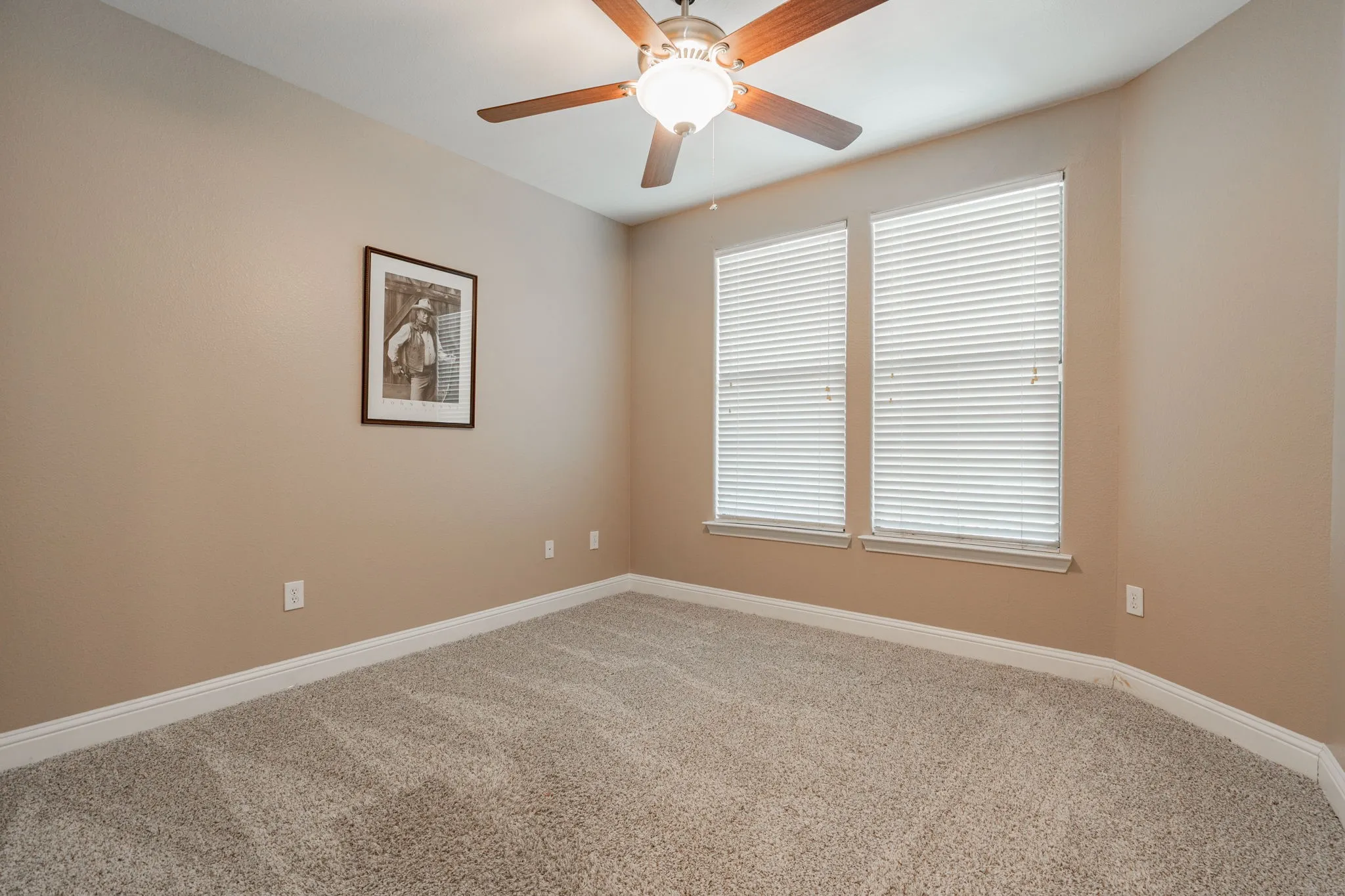 Spare room with carpet floors, baseboards, a ceiling fan, and plenty of natural light
