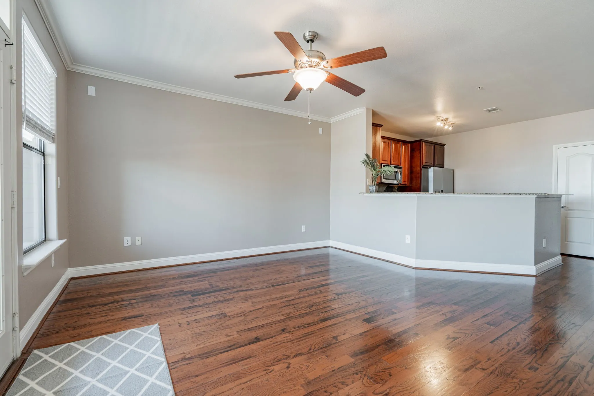 Unfurnished living room with dark wood finished floors, healthy amount of natural light, ceiling fan, baseboards, and ornamental molding