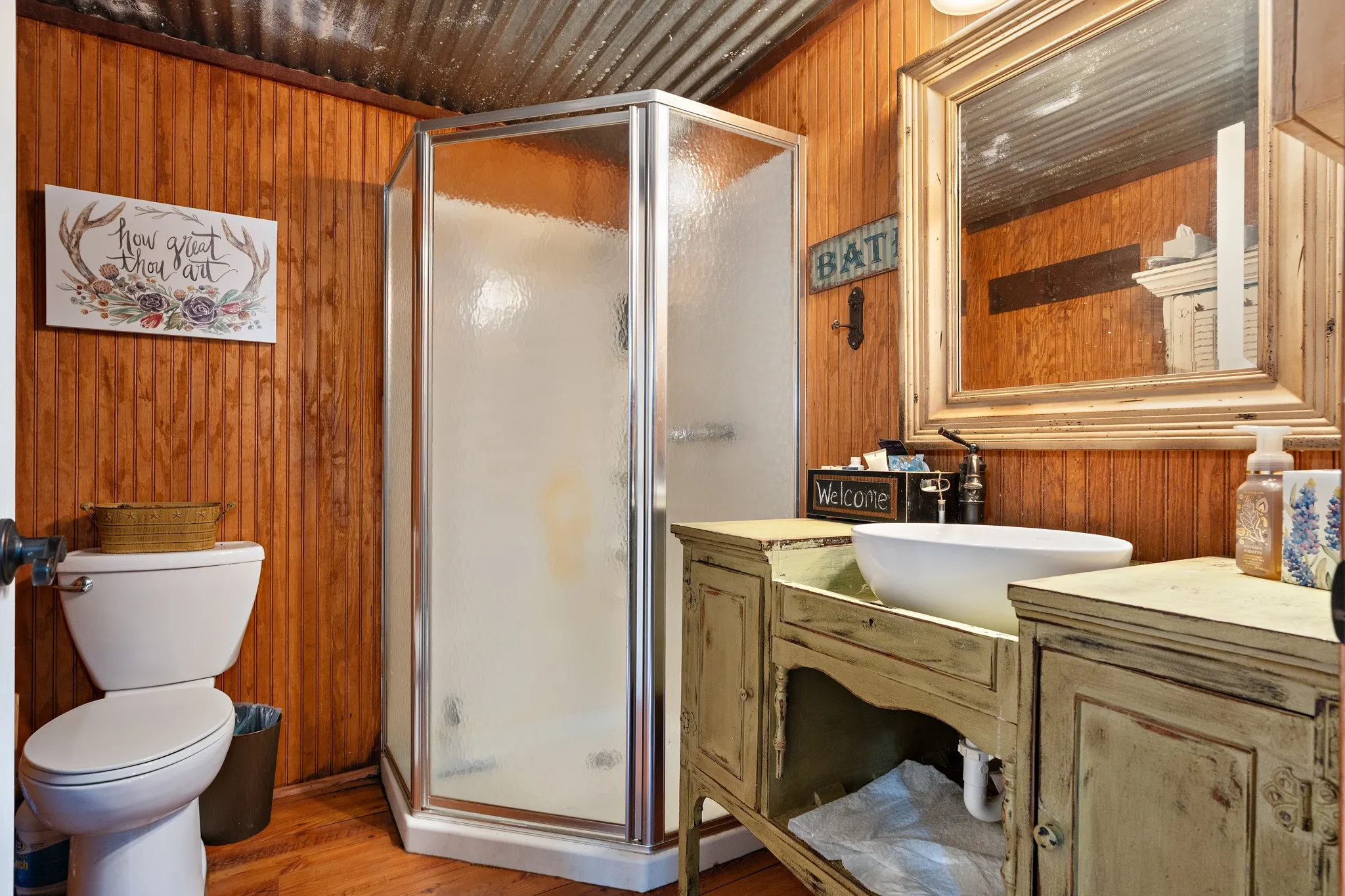Full bath with wooden walls, a stall shower, wood finished floors, vanity, and toilet
