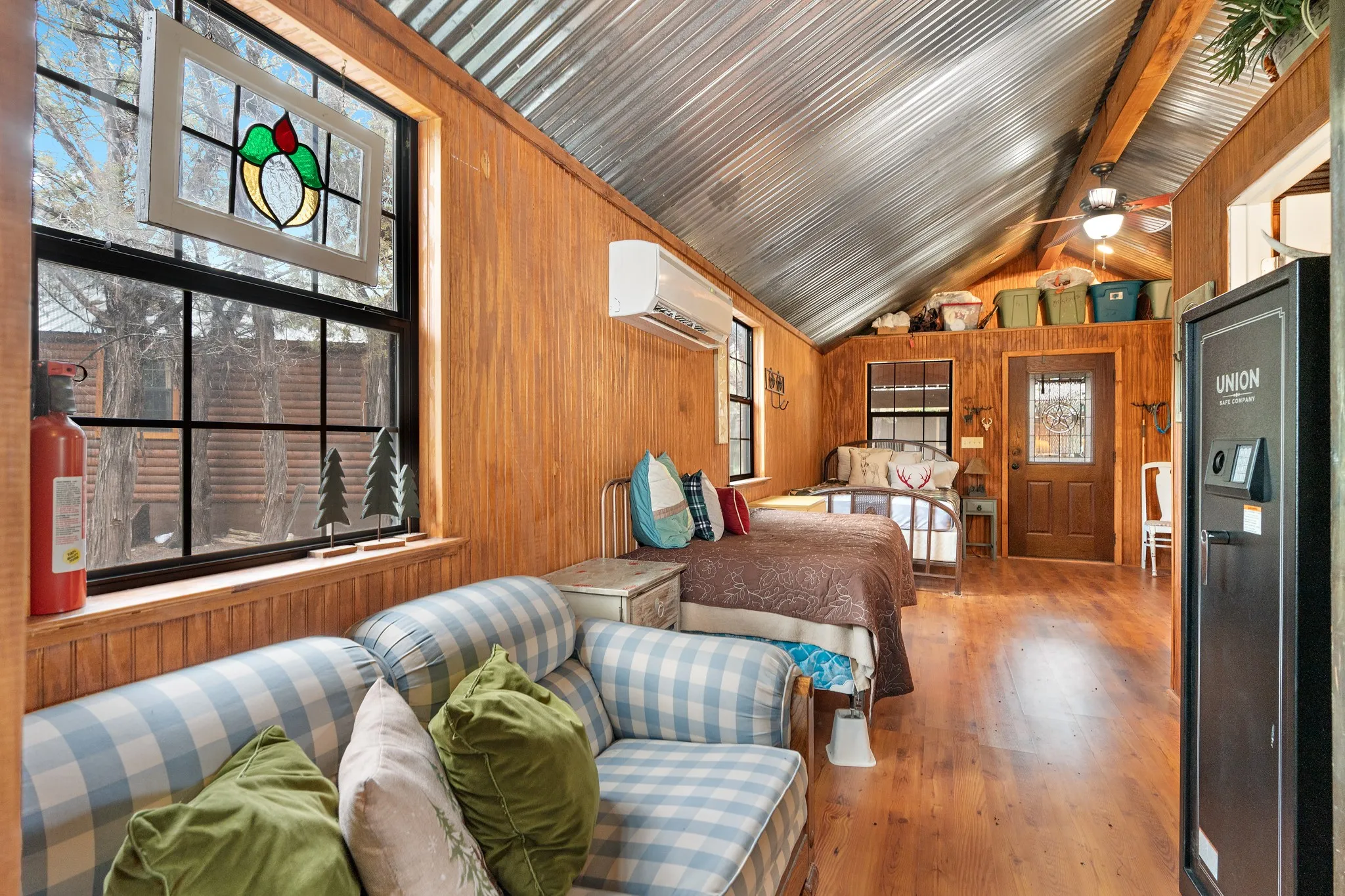 Bedroom featuring an AC wall unit, wooden walls, vaulted ceiling, and wood finished floors