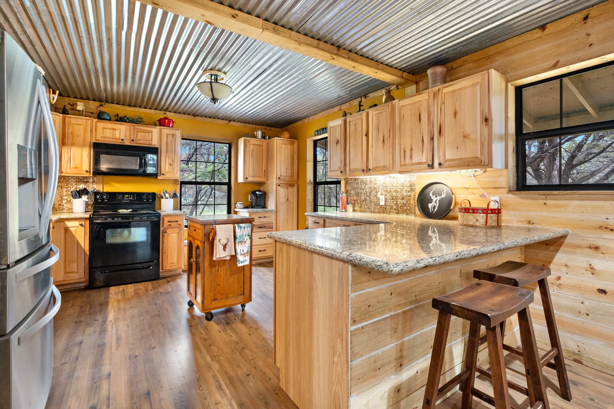 Kitchen with black appliances, a peninsula, backsplash, and light wood-style floors