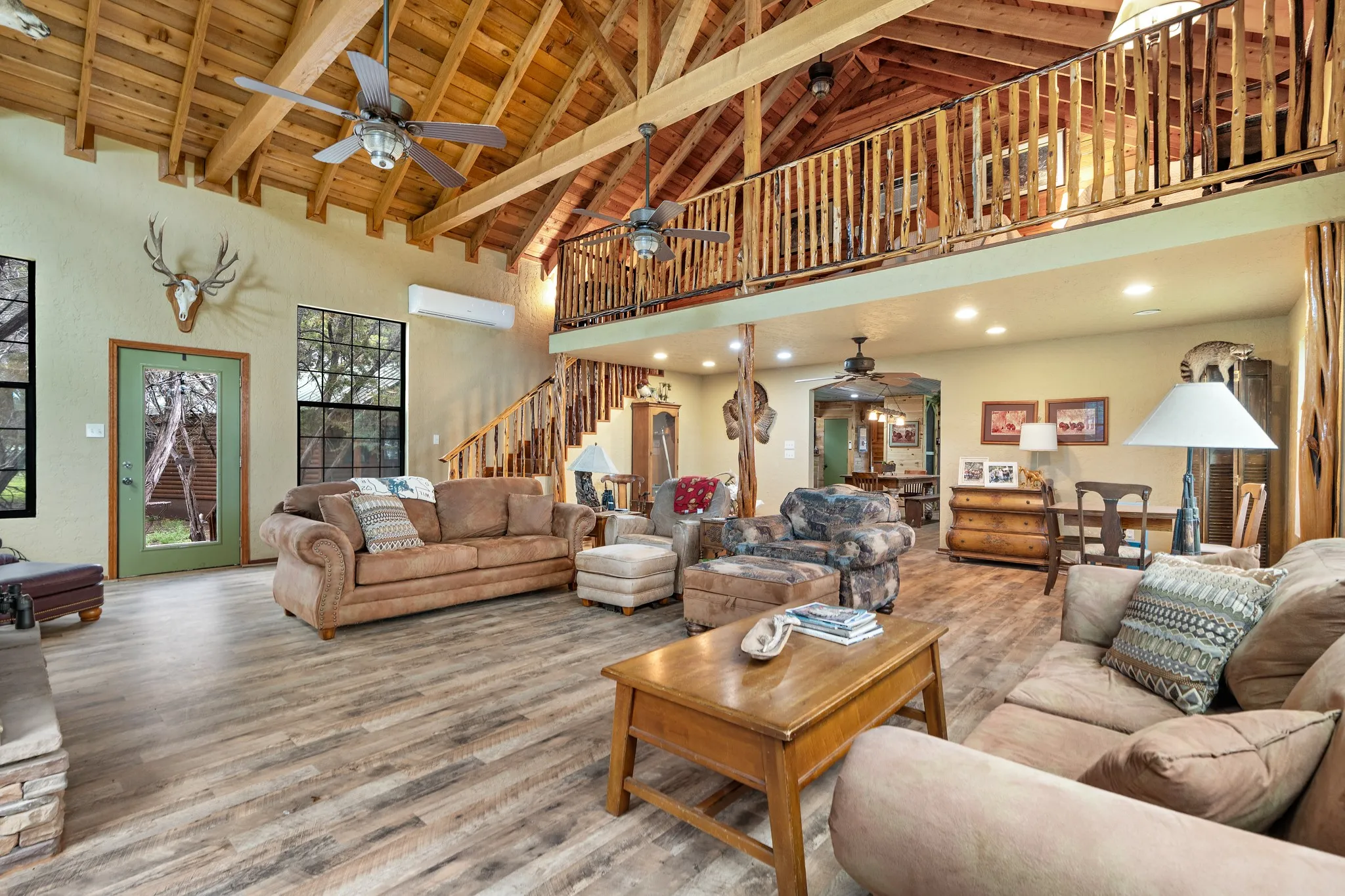 Living room with ceiling fan, stairway, wood finished floors, wooden ceiling, and high vaulted ceiling