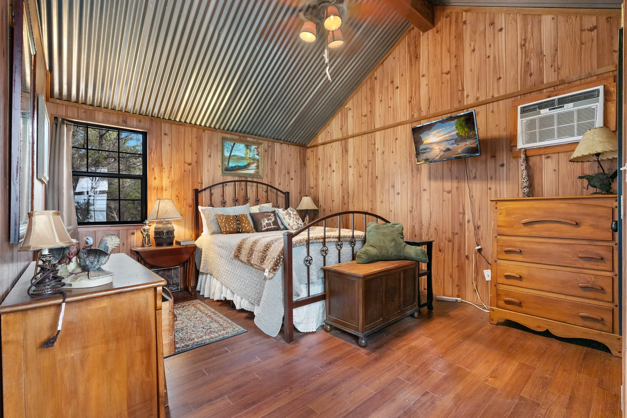 Bedroom with a wall mounted air conditioner, wooden walls, and wood finished floors