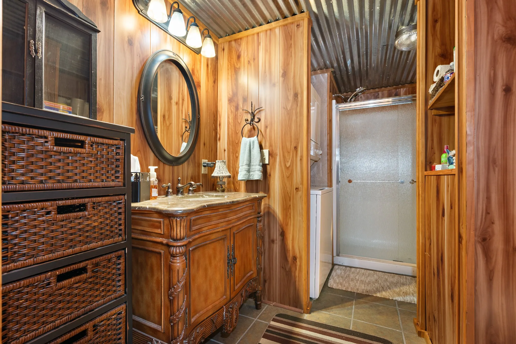 Full bathroom featuring tile patterned flooring, a shower stall, vanity, wood walls, and washer / dryer