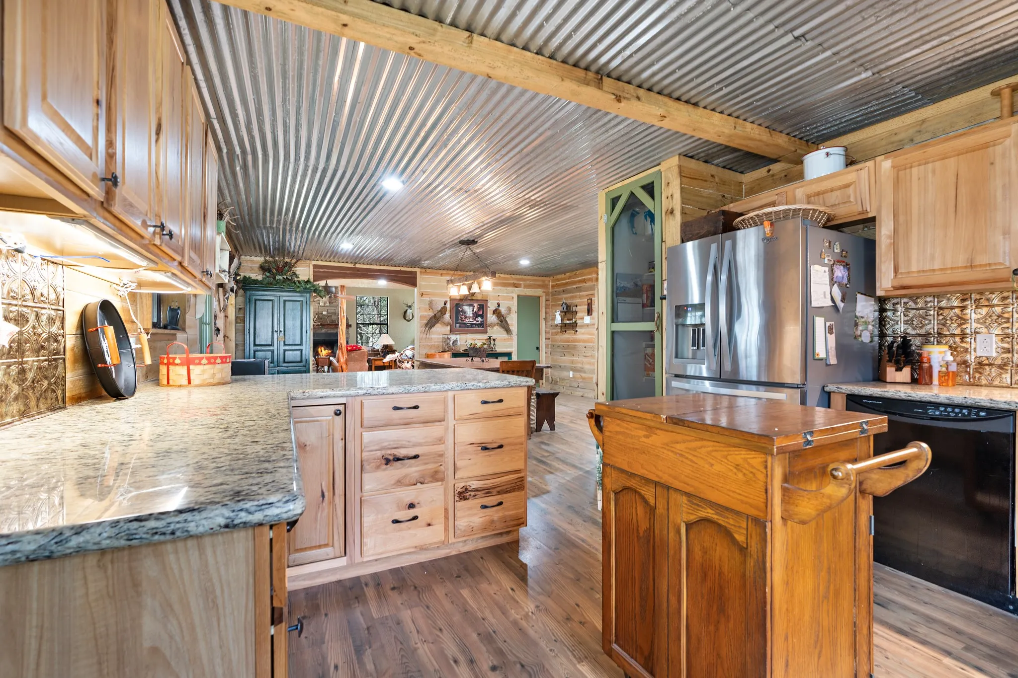 Kitchen with stainless steel refrigerator with ice dispenser, dishwasher, hardwood / wood-style flooring, light brown cabinets, and backsplash