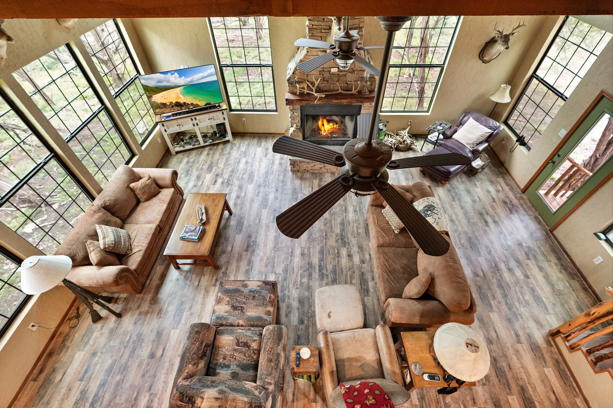 Living room featuring a ceiling fan, wood finished floors, a fireplace, and a towering ceiling