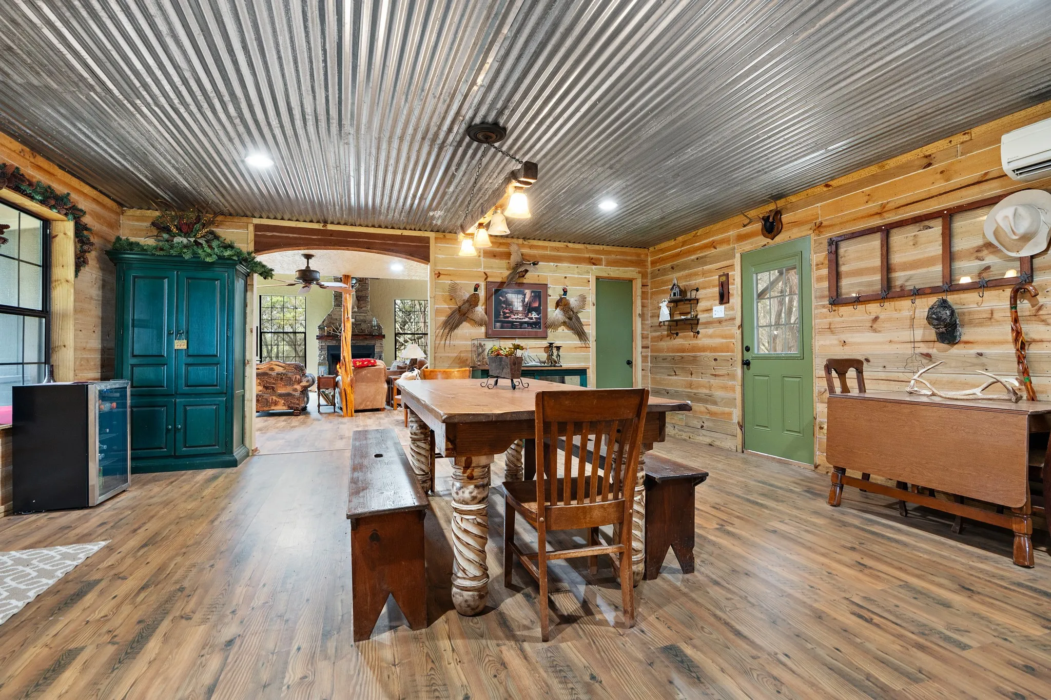 Dining area with wood finished floors, ceiling fan, wooden walls, and a wall mounted AC