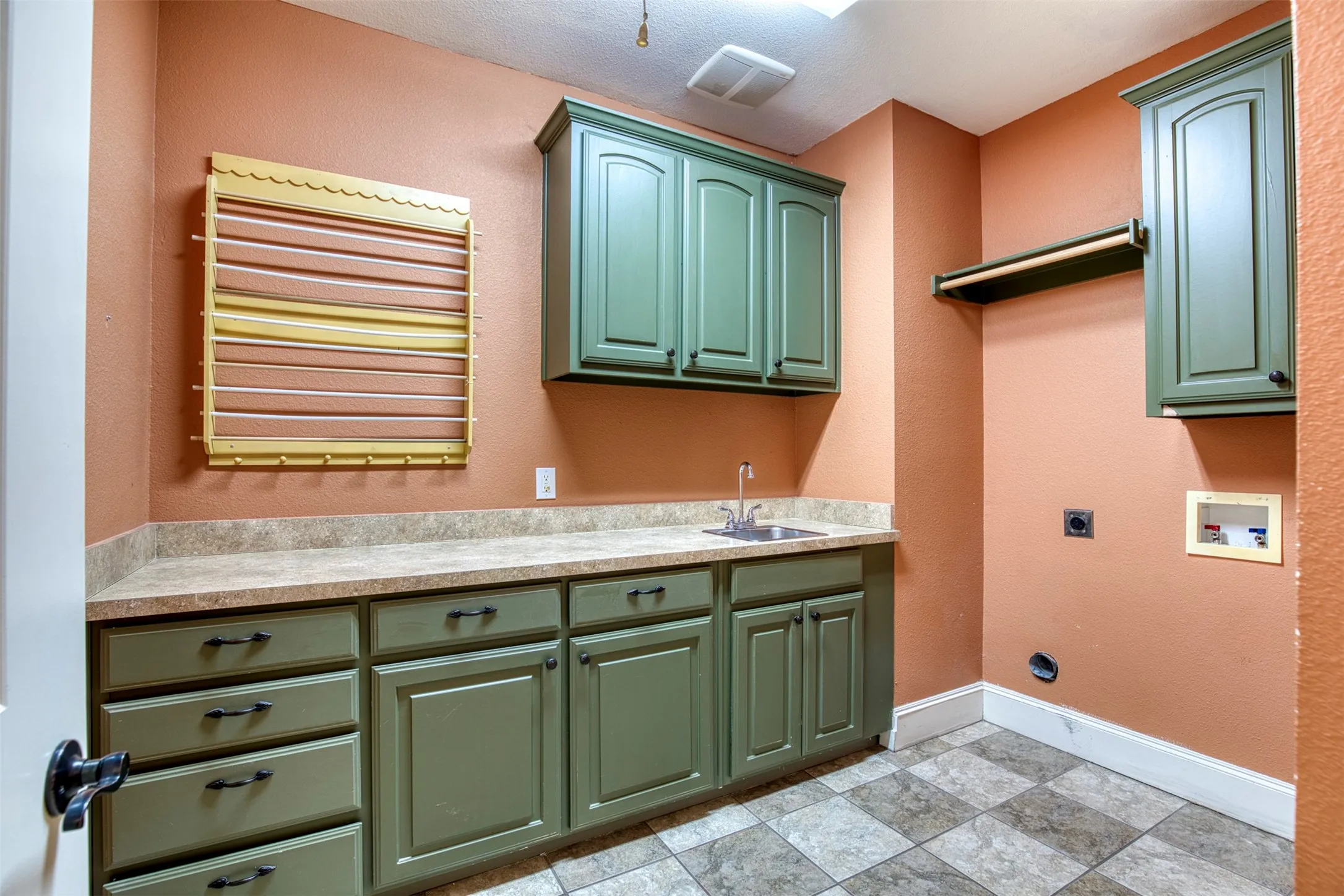Laundry room featuring cabinetry, counter, sink, and built-in dyer rack.
