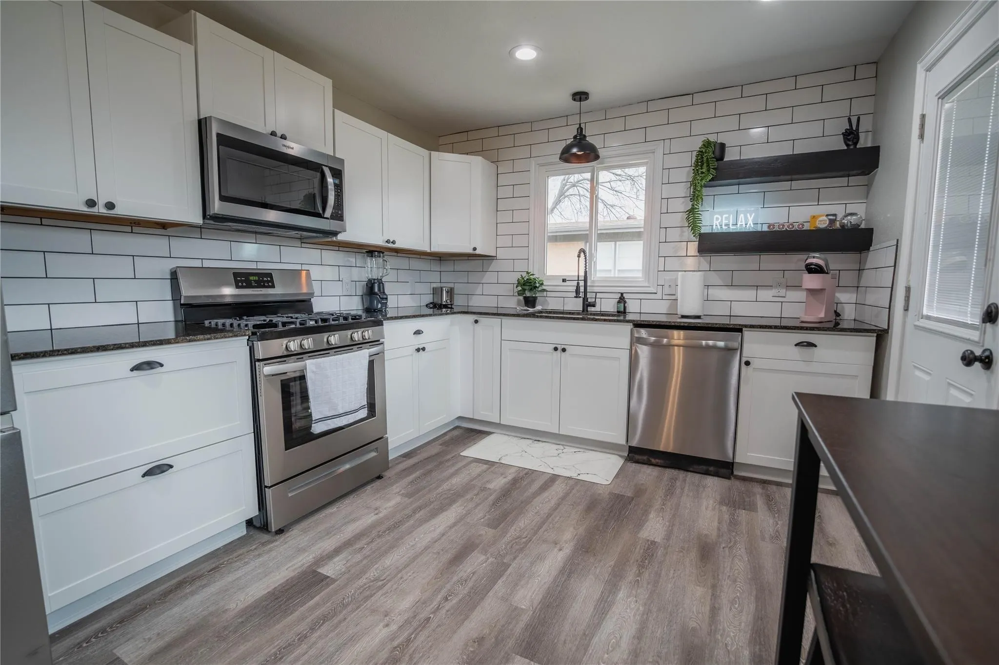 Kitchen featuring appliances with stainless steel finishes, decorative backsplash, light wood-type flooring, white cabinetry, and recessed lighting