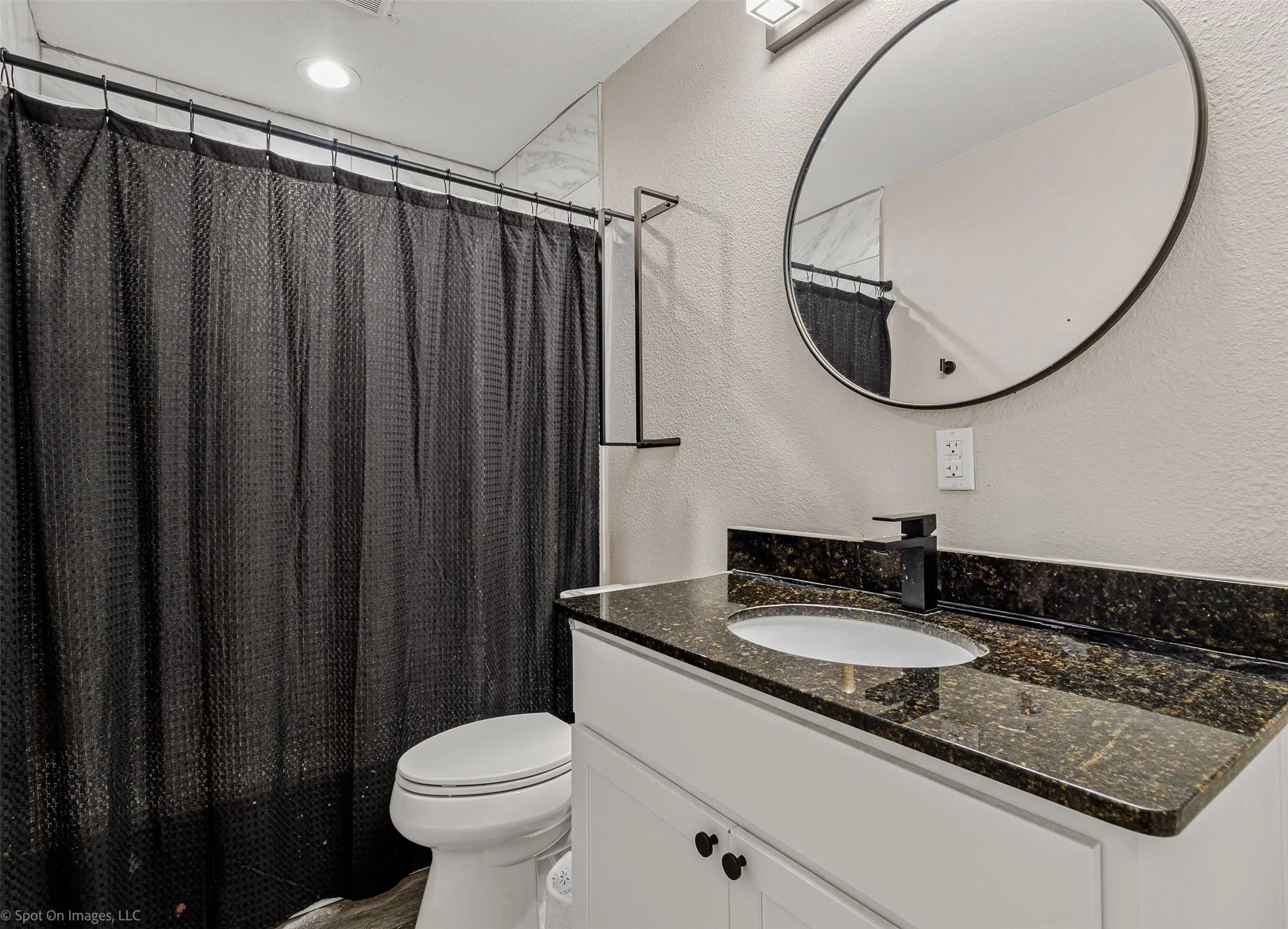 Bathroom featuring a textured wall, toilet, and vanity