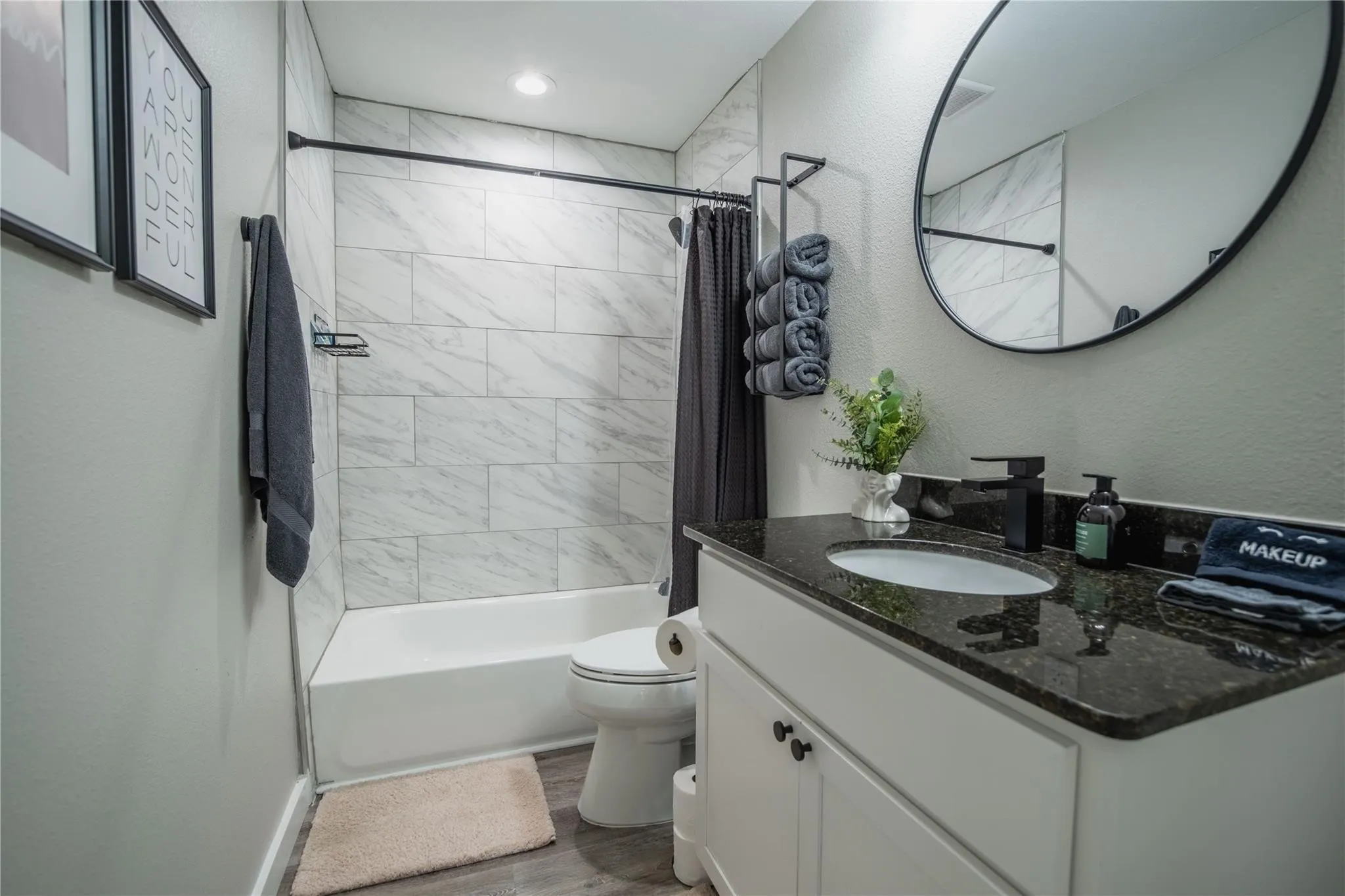 Bathroom with toilet, wood finished floors, vanity, and shower / bath combo