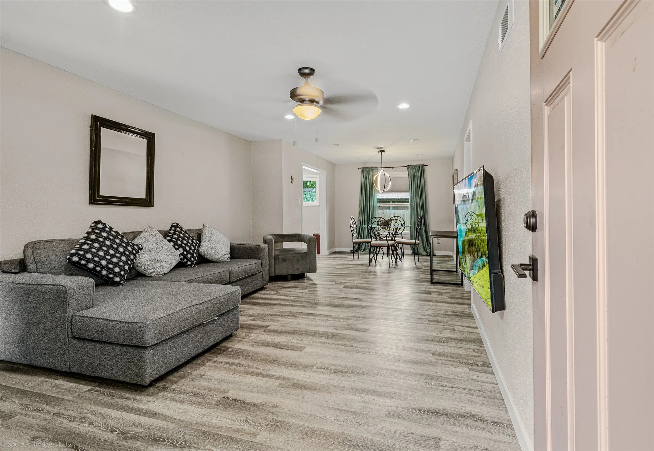 Living room with light wood finished floors, recessed lighting, ceiling fan, and baseboards
