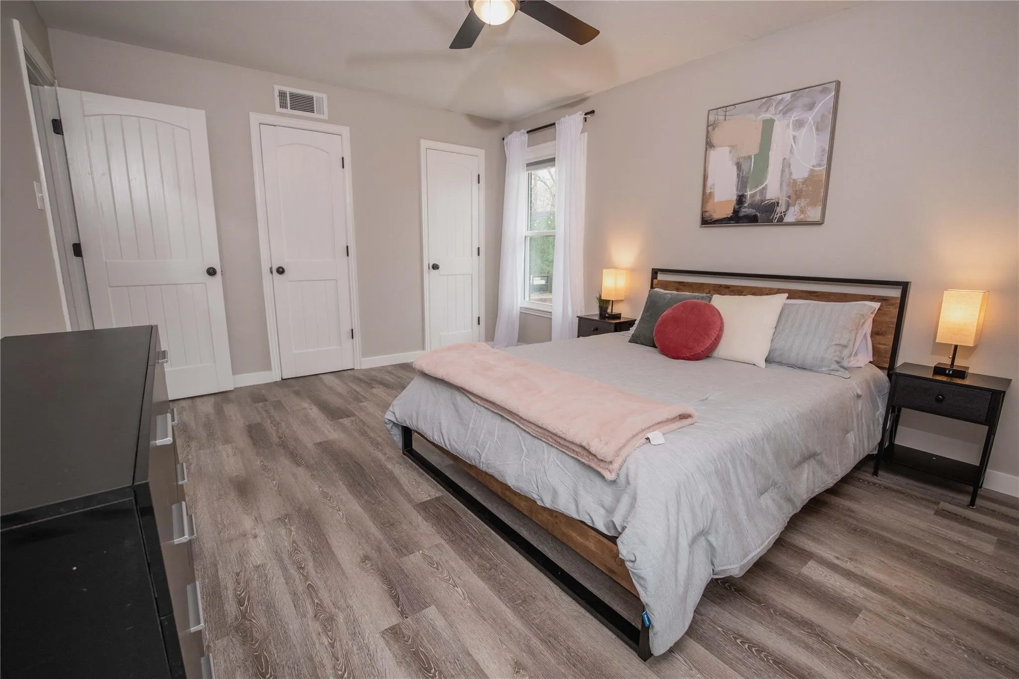 Bedroom featuring wood finished floors, baseboards, a ceiling fan, and multiple closets