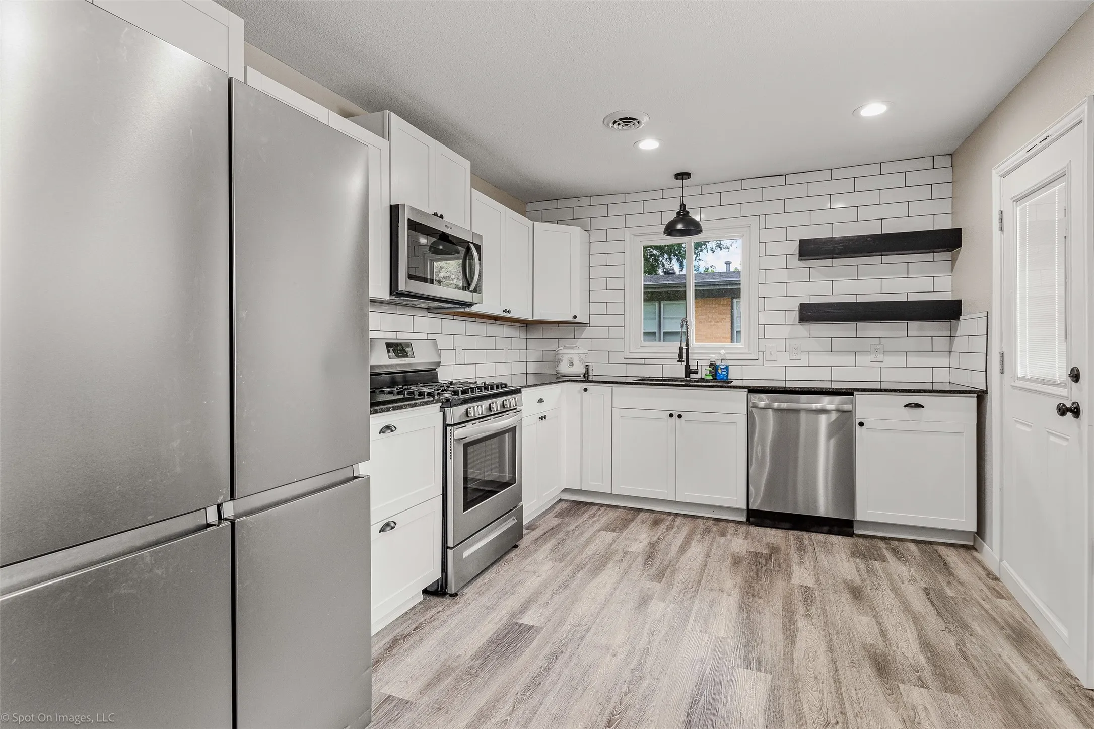 Kitchen featuring appliances with stainless steel finishes, a sink, dark countertops, open shelves, and recessed lighting