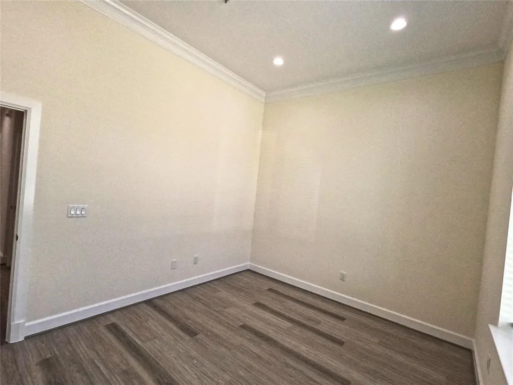 Unfurnished room featuring crown molding, dark wood finished floors, baseboards, and recessed lighting