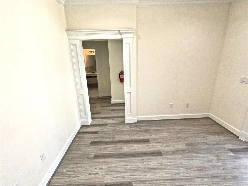Unfurnished room featuring dark wood-style flooring, baseboards, and ornamental molding