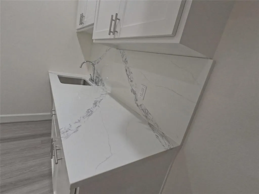 Detailed view of a sink, baseboards, and wood finished floors