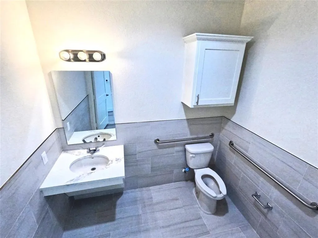 Bathroom with toilet, tile walls, and vanity