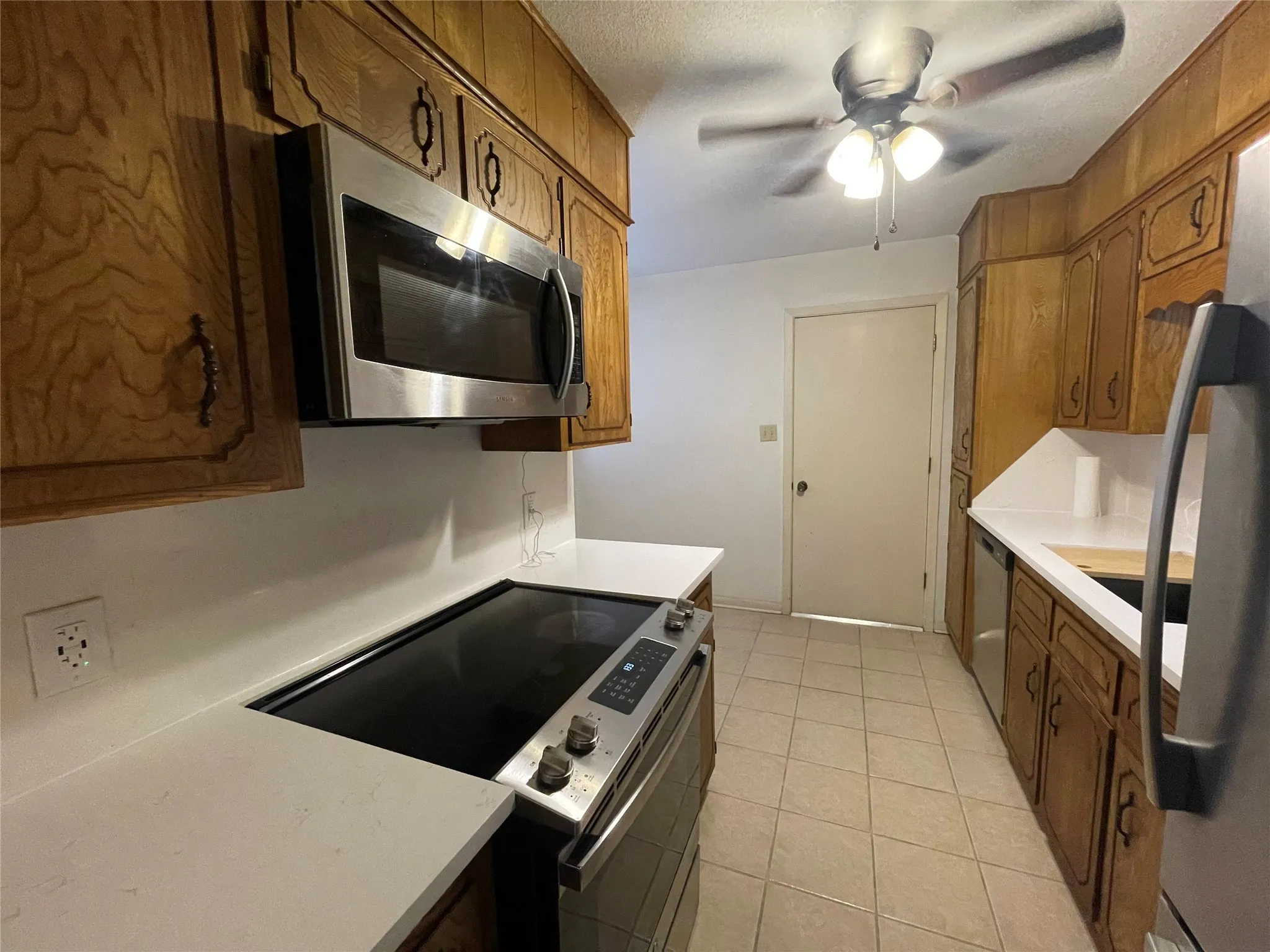 Kitchen featuring appliances with stainless steel finishes, light countertops, brown cabinets, and light tile patterned floors