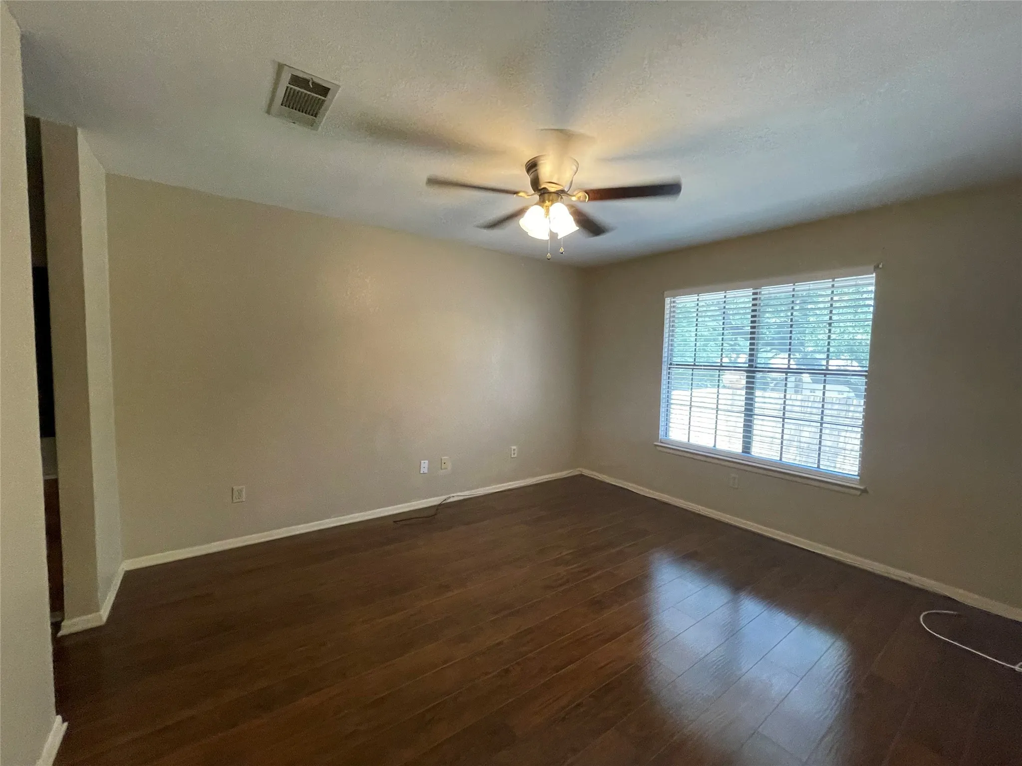 Empty room with baseboards, ceiling fan, and dark wood-style flooring