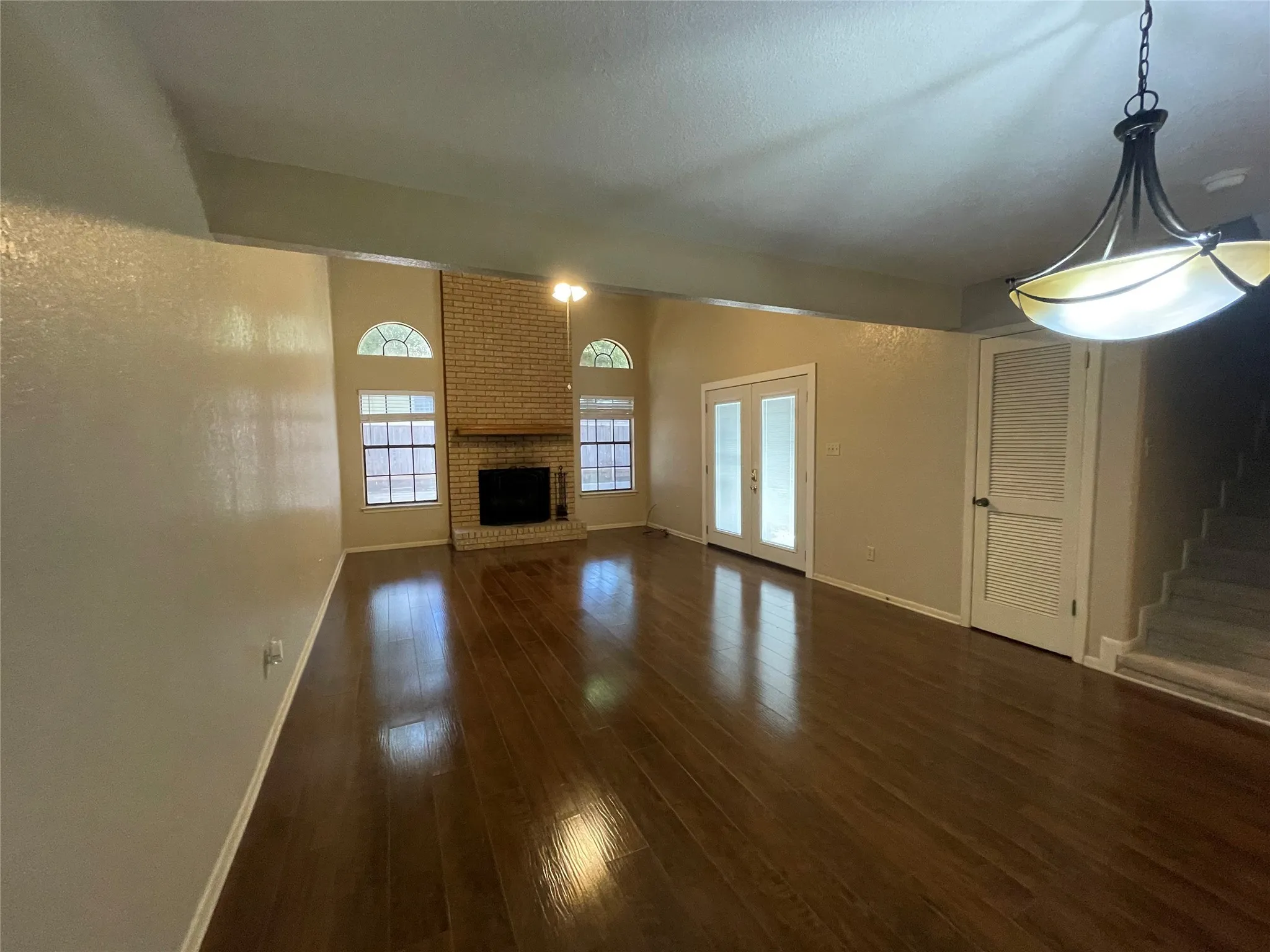 Unfurnished living room with dark wood-style flooring, baseboards, a fireplace, and stairs