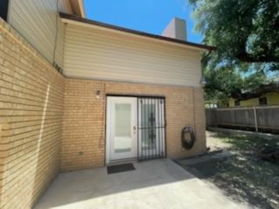 Back of house featuring brick siding, a chimney, fence, and a patio area