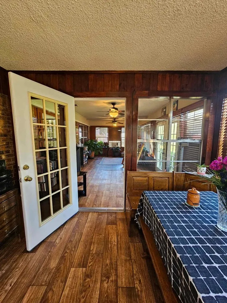 Dining space featuring wood walls, wood-type flooring, a textured ceiling, and a ceiling fan