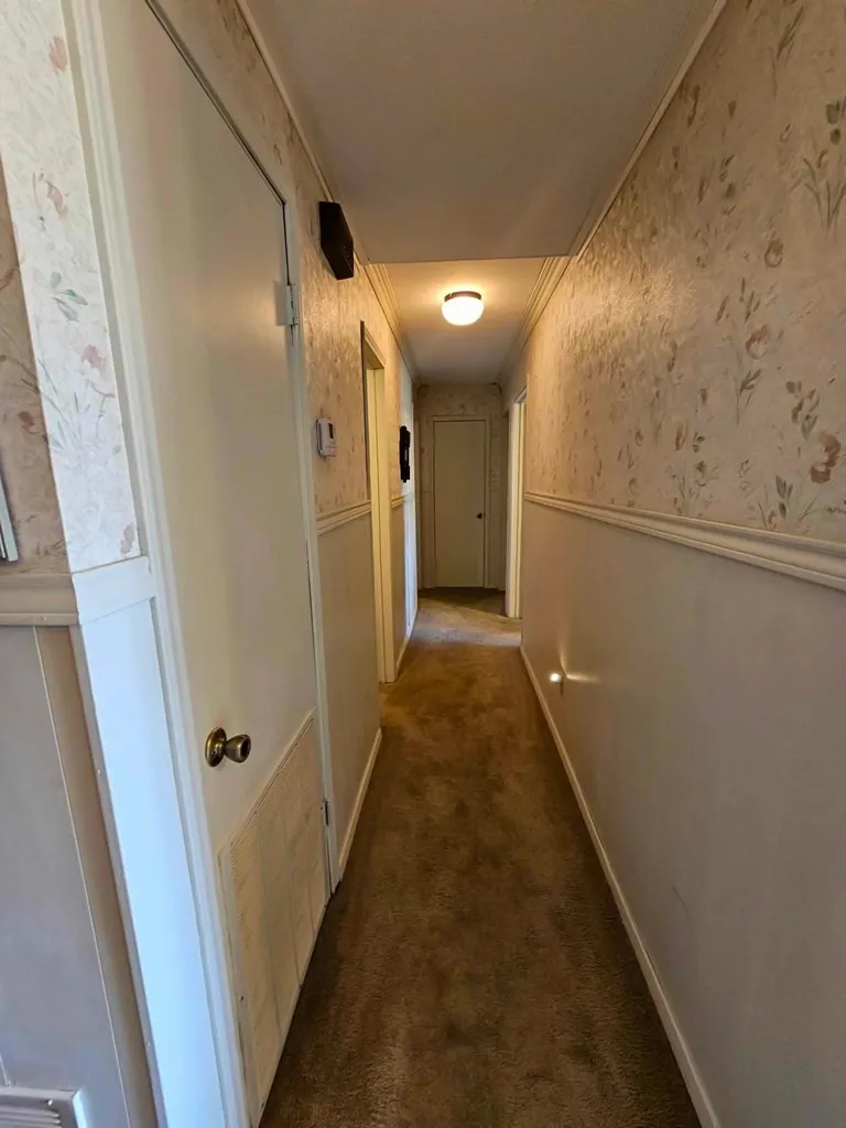Hallway with wainscoting, wallpapered walls, and carpet