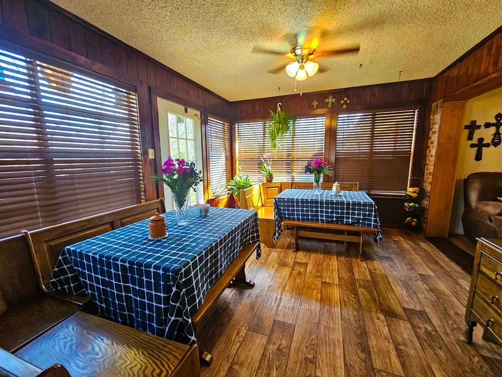 Dining area with hardwood / wood-style flooring, a ceiling fan, a textured ceiling, and wooden walls