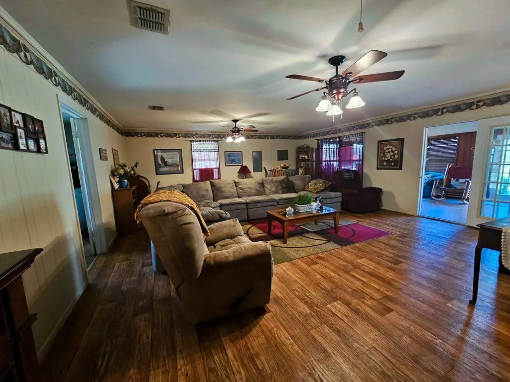 Living area with wood finished floors, a ceiling fan, and ornamental molding