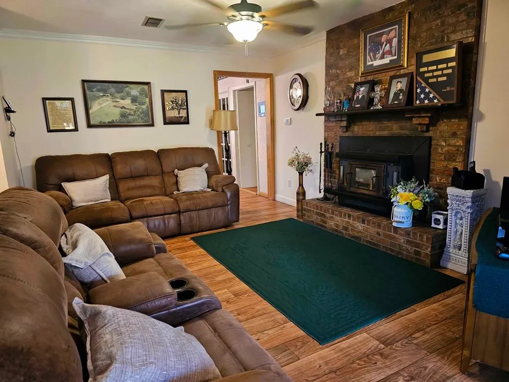 Living area featuring a ceiling fan, crown molding, wood finished floors, and baseboards
