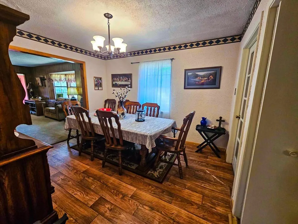 Dining area featuring a textured ceiling, a chandelier, dark wood-style flooring, and a textured wall