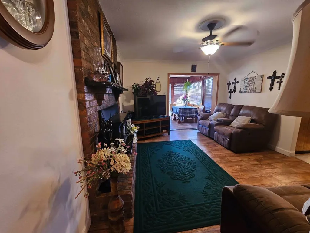 Living area featuring ceiling fan, wood finished floors, a fireplace, and baseboards