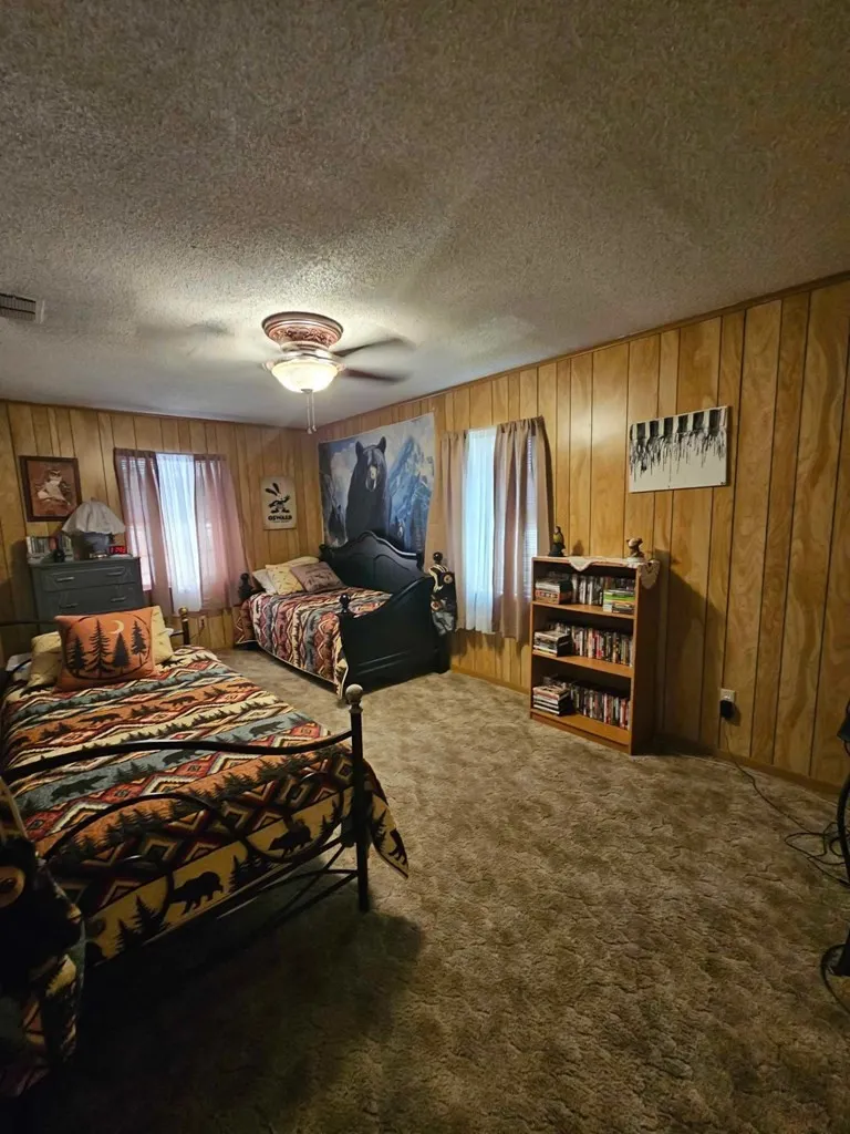 Carpeted bedroom with wood walls and a textured ceiling