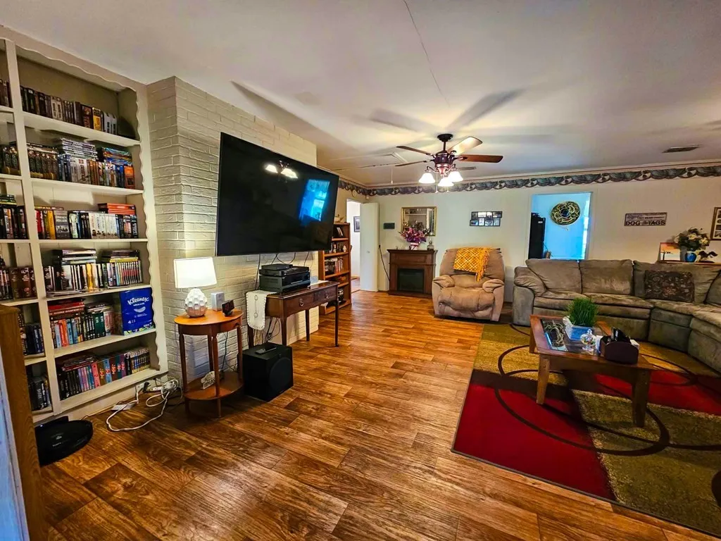 Living room featuring wood finished floors, ceiling fan, and a fireplace