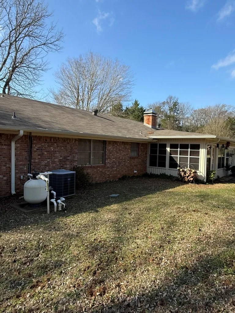 Back of house with brick siding, a sunroom, a chimney, and a yard