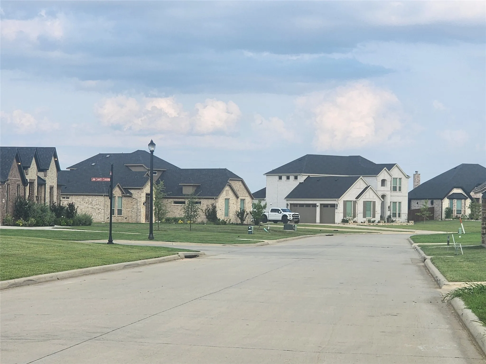 View of concrete street with curbs, a residential view, and street lights